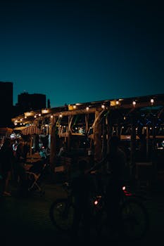A bustling night market scene, illuminated by warm lights and crowded with people enjoying the evening.