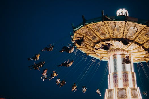 Illuminated carousel swing ride at night with people enjoying the thrill.