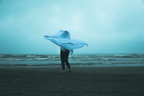 Person Standing Barefoot on a Beach in Wind 