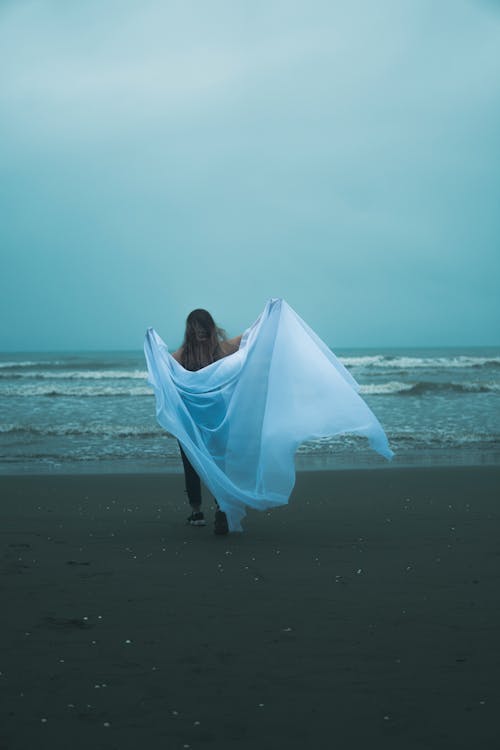 A Person Holding a White Cloth on the Beach