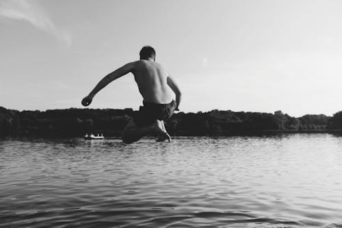 Monochrome Photography of Man Jumping into The Water