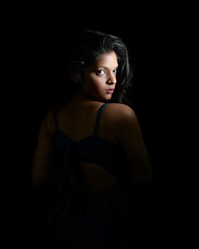 Elegant studio portrait of a woman with striking lighting, highlighting her features.