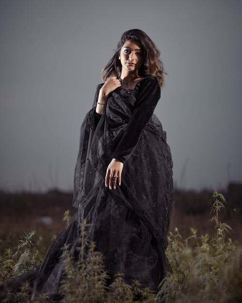 Woman in Black Lace Dress Standing on Grass Field