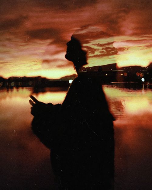 Free Silhouette of a person with a dramatic sunset sky reflected in a tranquil lake at Worcester, South Africa. Stock Photo