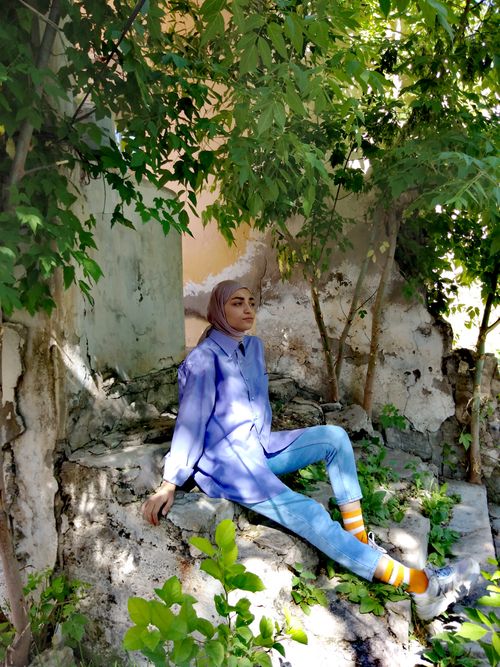 Free A woman relaxes outdoors in a lush, shadow-dappled garden, enjoying the warmth of a sunny day. Stock Photo