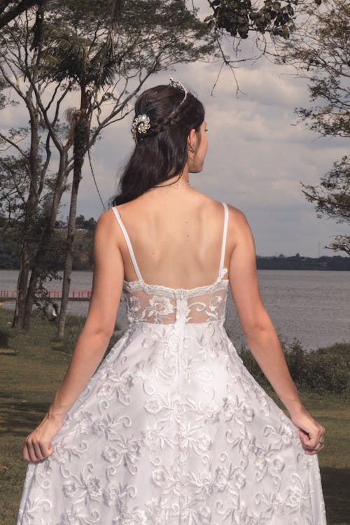Woman in White Lace Dress Standing Near a Lake