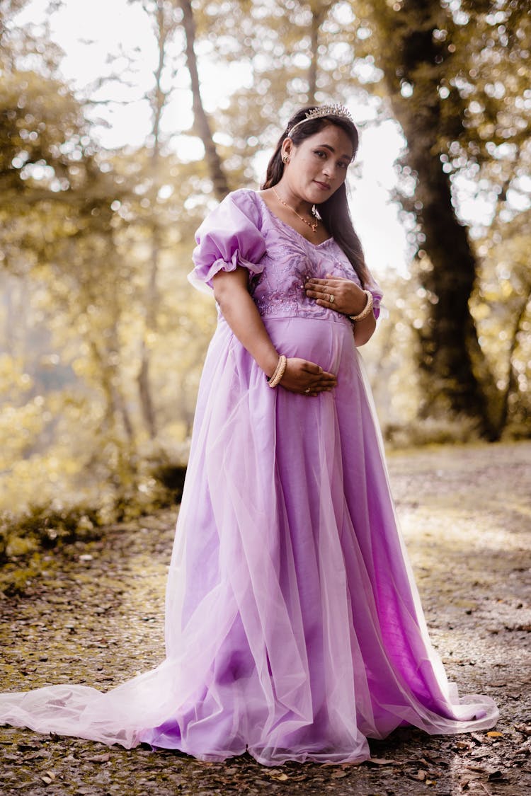 Pregnant Woman In Purple Dress Holding Her Tummy