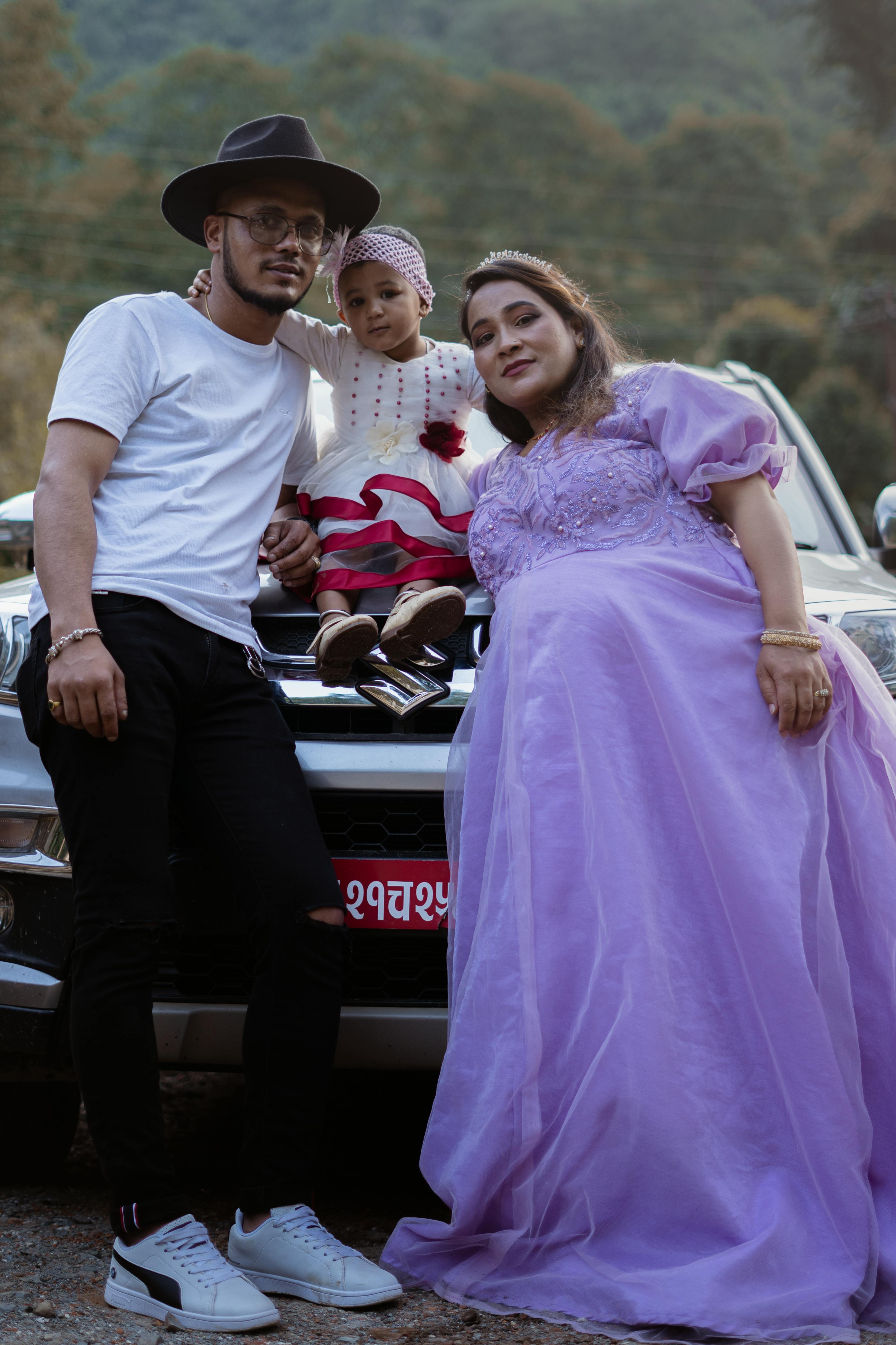 a couple and their affectionate daughter in front of a car