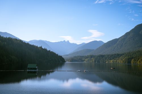 Free Peaceful lake surrounded by towering mountains under a clear blue sky. Stock Photo