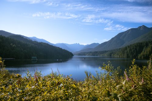Free Breathtaking view of Capilano Lake surrounded by mountains, showcasing serene nature and vibrant greenery. Stock Photo