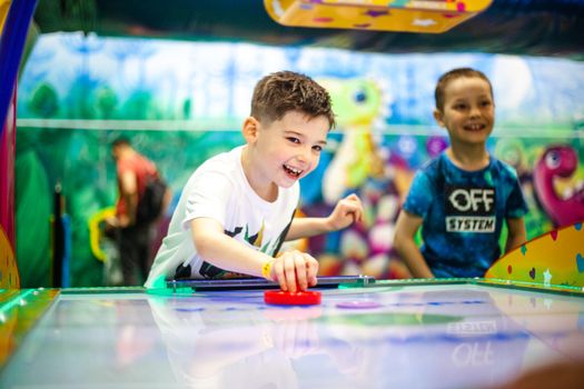 Two kids having fun playing air hockey at an indoor arcade in Moscow.