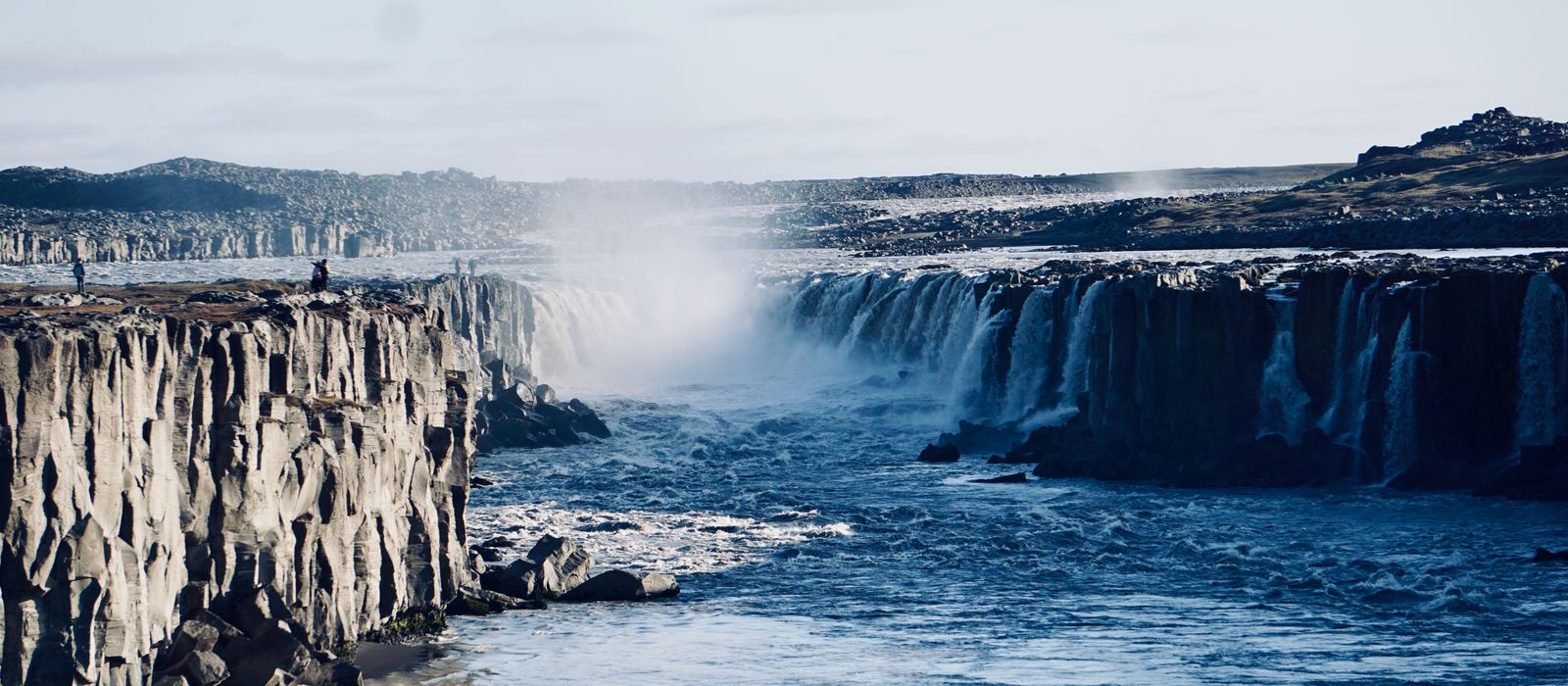 Breathtaking view of Selfoss waterfall cascading over Iceland's dramatic rocky cliffs under a clear sky.