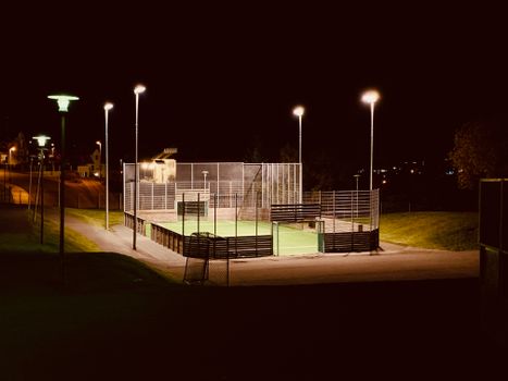 Scenic view of a brightly lit football field in Akureyri, Iceland, during a calm night.