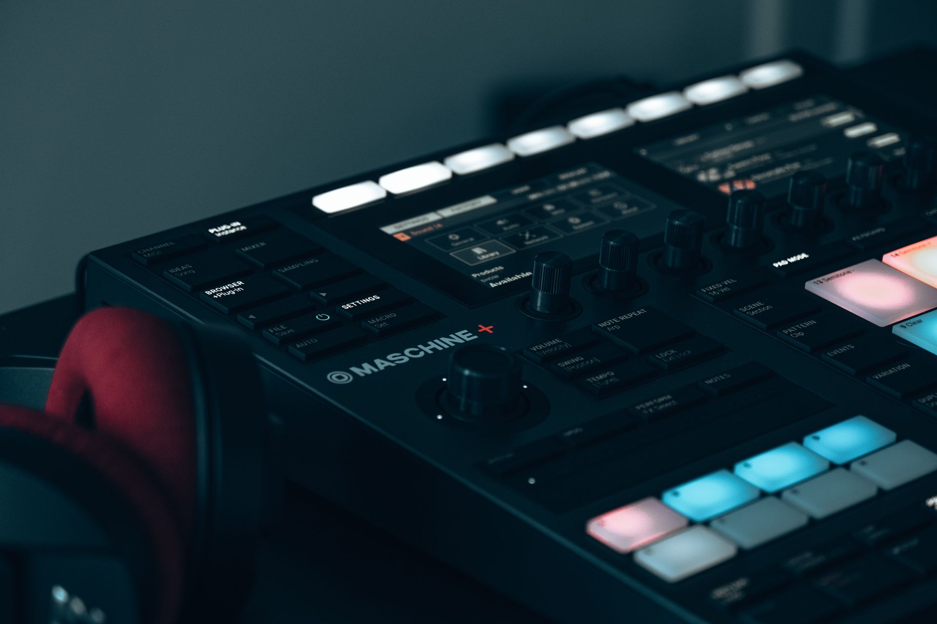 Detailed view of a digital drum machine in a studio setting with headphones in the foreground.