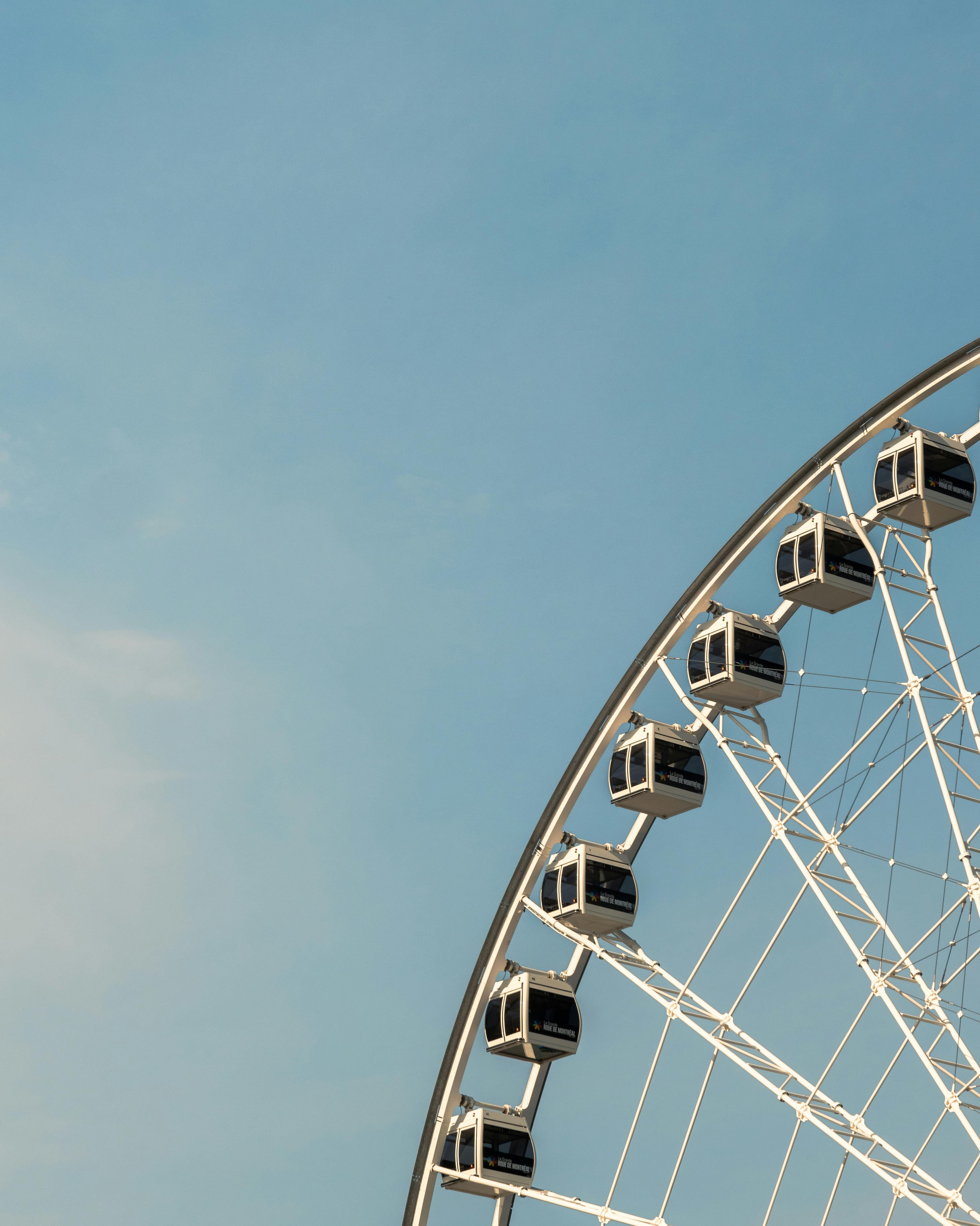 A picturesque view of a Ferris wheel set against a bright blue sky in Montreal, QC, Canada.