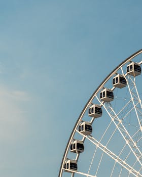 A picturesque view of a Ferris wheel set against a bright blue sky in Montreal, QC, Canada.