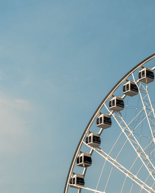 A picturesque view of a Ferris wheel set against a bright blue sky in Montreal, QC, Canada.