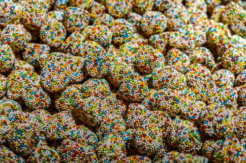 Free A vibrant close-up of assorted candies covered in multicolored sugar sprinkles. Stock Photo