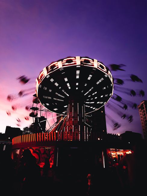 A vibrant swing ride in motion during dusk at an amusement park, capturing thrilling motion and colorful lights.