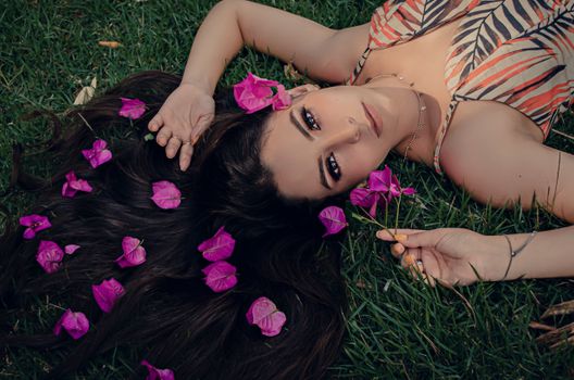 A Woman with Long Black Hair Lying on a Grassy Ground while Looking at the Camera