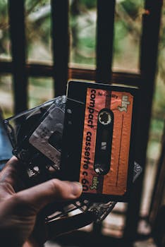 A nostalgic close-up of a hand holding vintage cassette tapes against a blurred background.