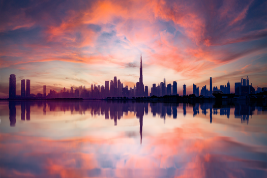 A breathtaking view of Dubai's skyline reflected in water during a vivid sunset, highlighting the urban architecture.