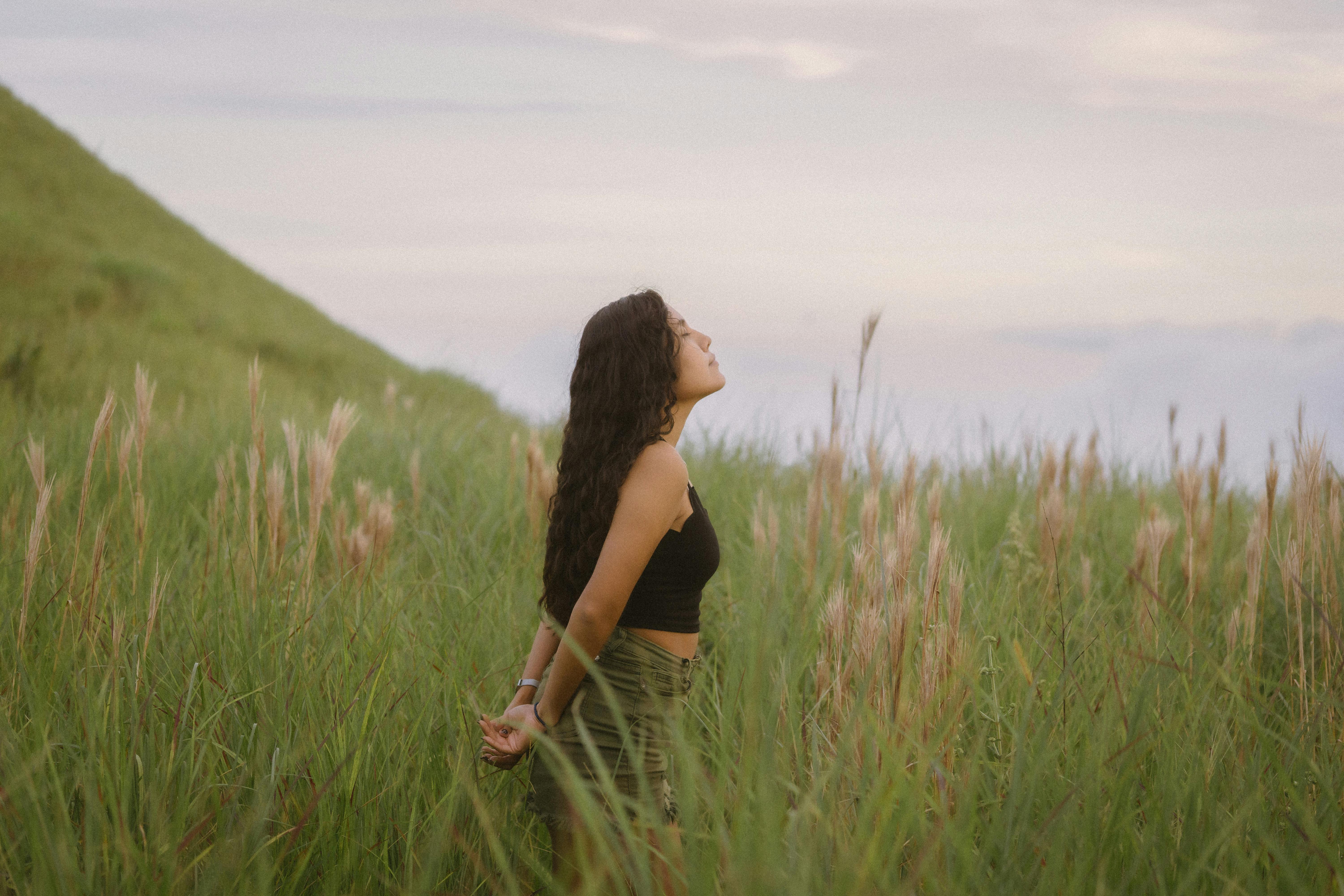 girl with long brown hair standing in grassland