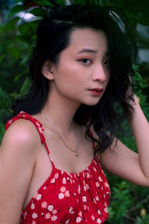 Free Charming portrait of a young woman wearing a floral dress surrounded by greenery. Stock Photo