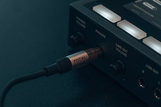 Detailed view of audio cable connected to electronic device, capturing modern technology essence.