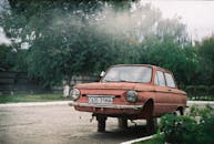 在乌克兰卢汉斯克的一条绿树环绕的街道上，停着一辆生锈的老爷车，展现了苏联时代的设计