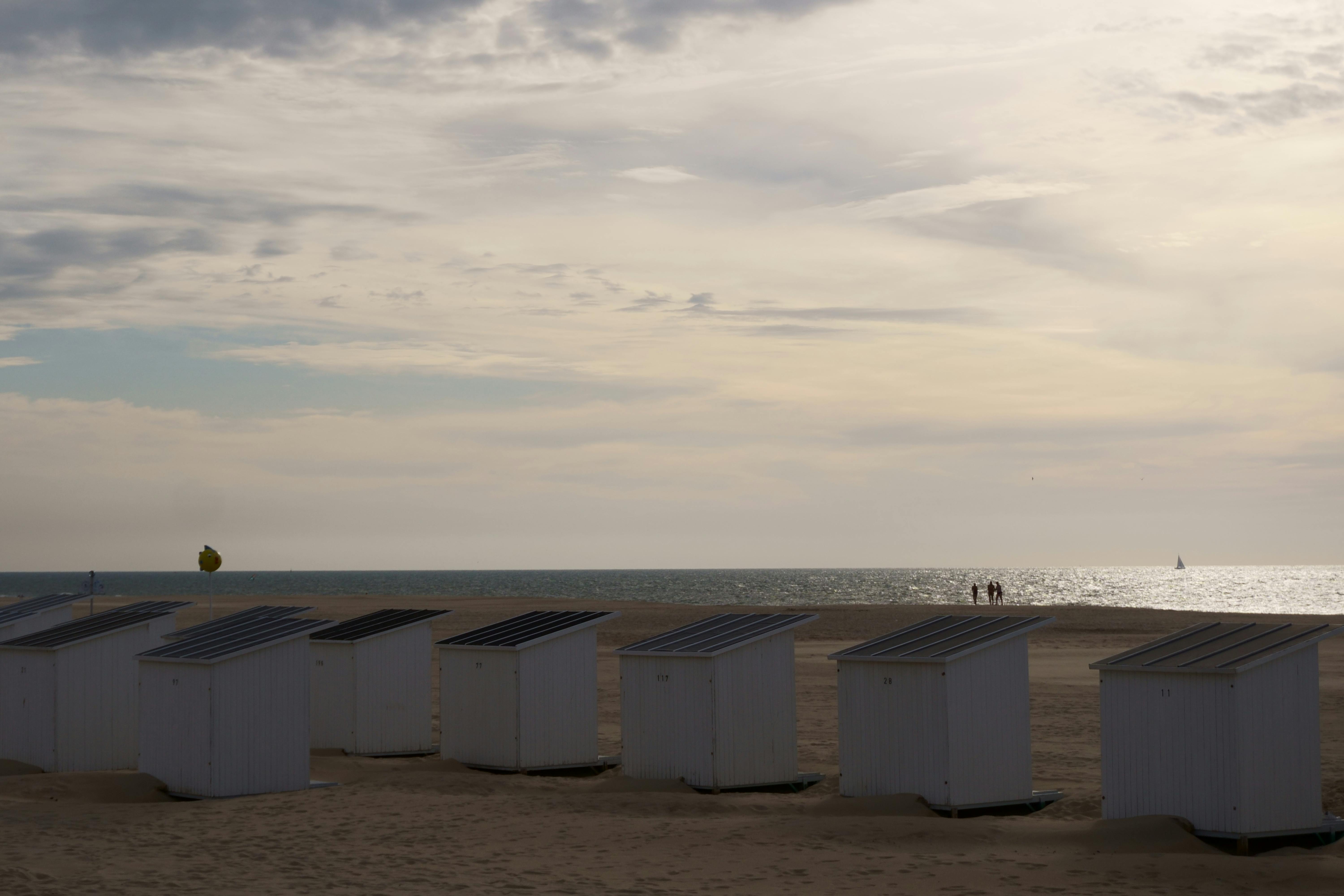 Serene beach scene at Oostende with cabanas, ocean, and a tranquil summer sky.
