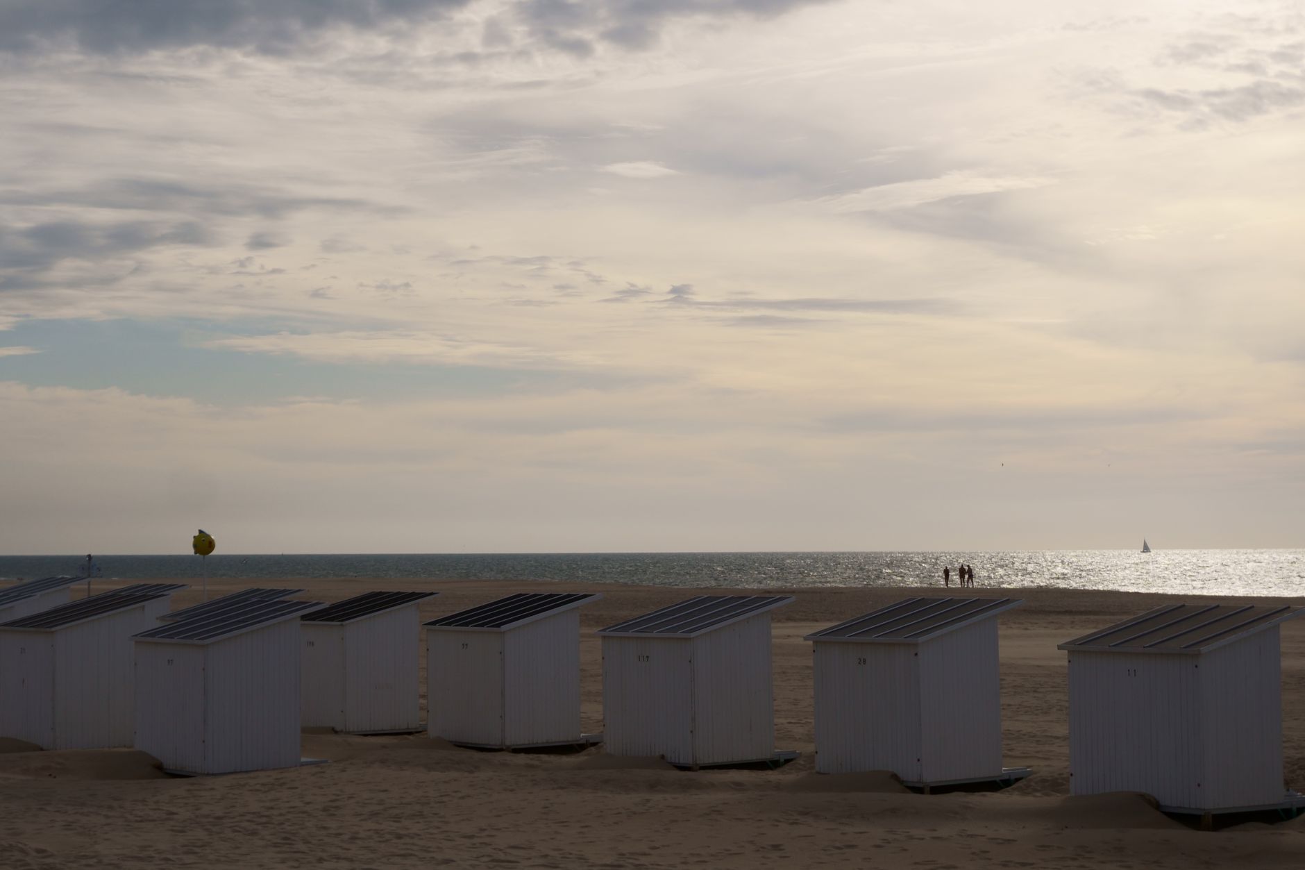 Serene beach scene at Oostende with cabanas, ocean, and a tranquil summer sky.