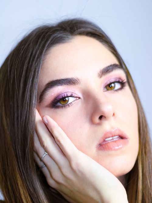 Free Close-up portrait of a young woman with hand on chin, showcasing natural beauty and elegance. Stock Photo