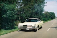 在俄罗斯萨哈林州宁静的高速公路上，一辆经典汽车行驶在郁郁葱葱的绿树环绕之中