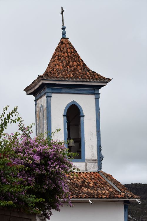 Free View of a historic church bell tower in Diamantina, Brazil, with purple flowers in the foreground. Stock Photo