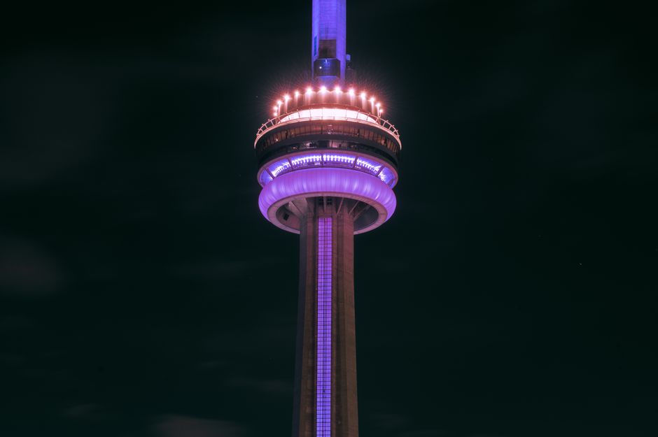 Close-up of the CN Tower beautifully illuminated at night against a dark sky in Toronto, Canada.