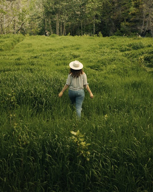 A Woman Walking on the Grass Field