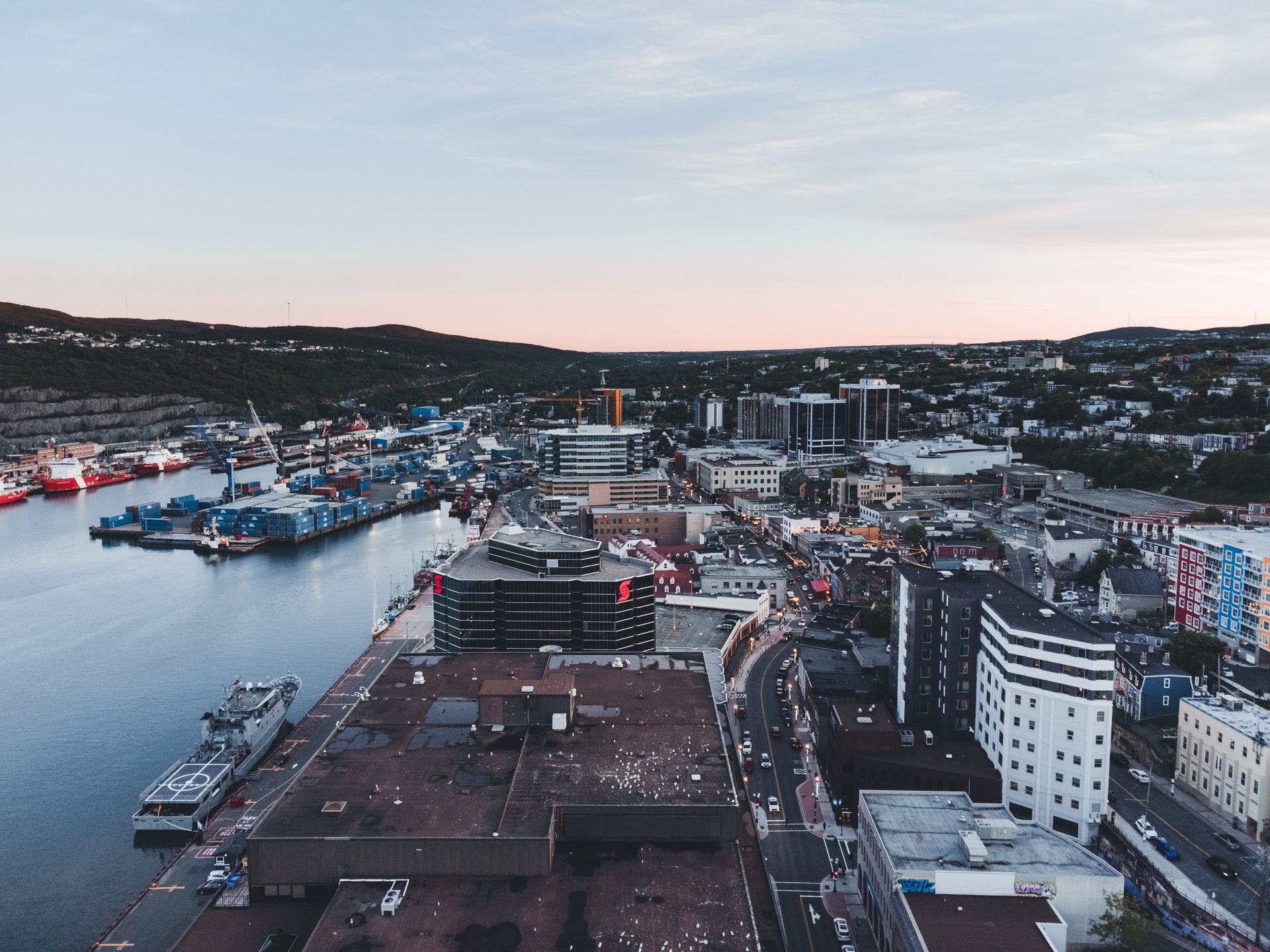 A beautiful urban harbor scene captured from above, showcasing buildings and a marina at sunset.