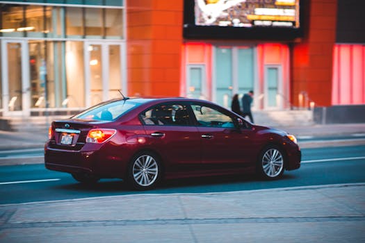 A red sedan car traveling swiftly through a modern cityscape with colorful architecture.