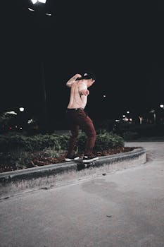 Skilled skateboarder performing a trick at night on an urban street.