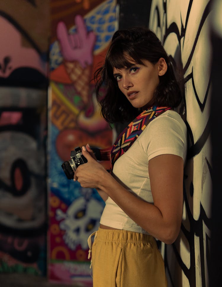 Woman Leaning On A Wall While Holding A Camera