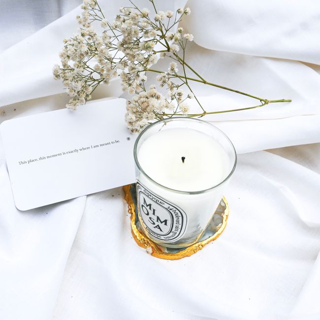 A serene composition featuring a candle and baby's breath on a white fabric backdrop.