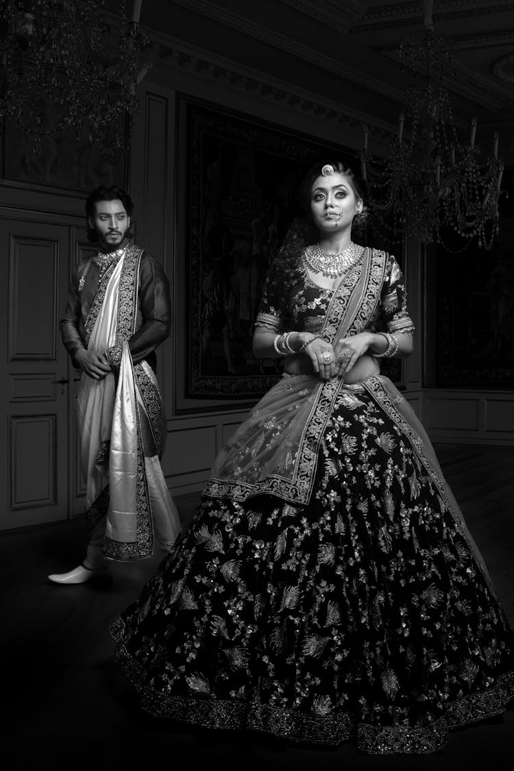 Grayscale Photography Of A Man And A Woman Wearing Traditional Clothing While Standing Near Each Other