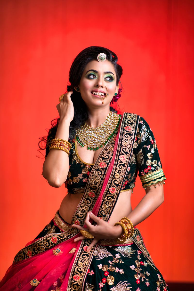 Smiling woman in Indian attire posing against a vibrant red background.