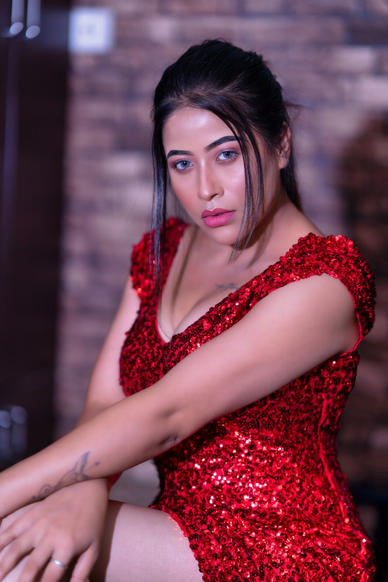 Portrait of a woman wearing a sparkling red sequin dress against a blurred indoor background.