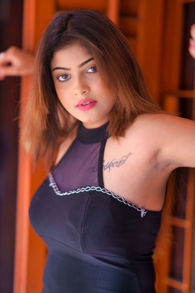Elegant young woman posing indoors wearing a chic black outfit, showcasing modern fashion.