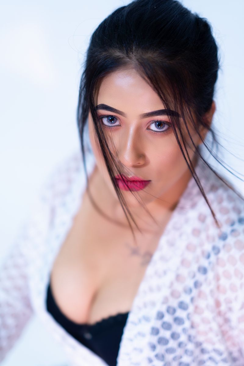 Portrait of a woman with striking eyes and red lipstick wearing a lace cardigan. High angle shot with a serious expression.