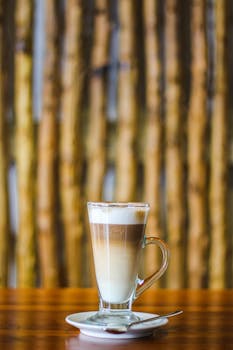 Enjoy a delightful latte served in a glass cup against a bamboo backdrop. Perfect for coffee lovers.