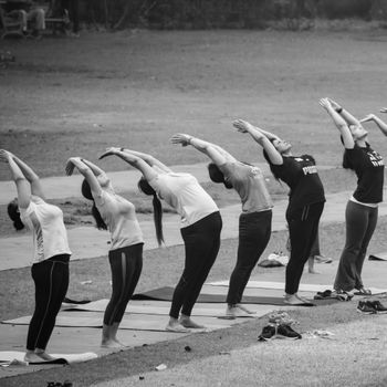 A group of women practicing yoga together outdoors, focusing on flexibility and healthy living.