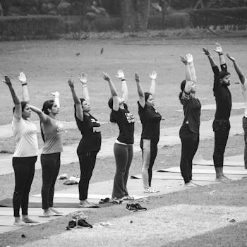 A group of people practicing yoga outdoors, captured in a black and white photograph.